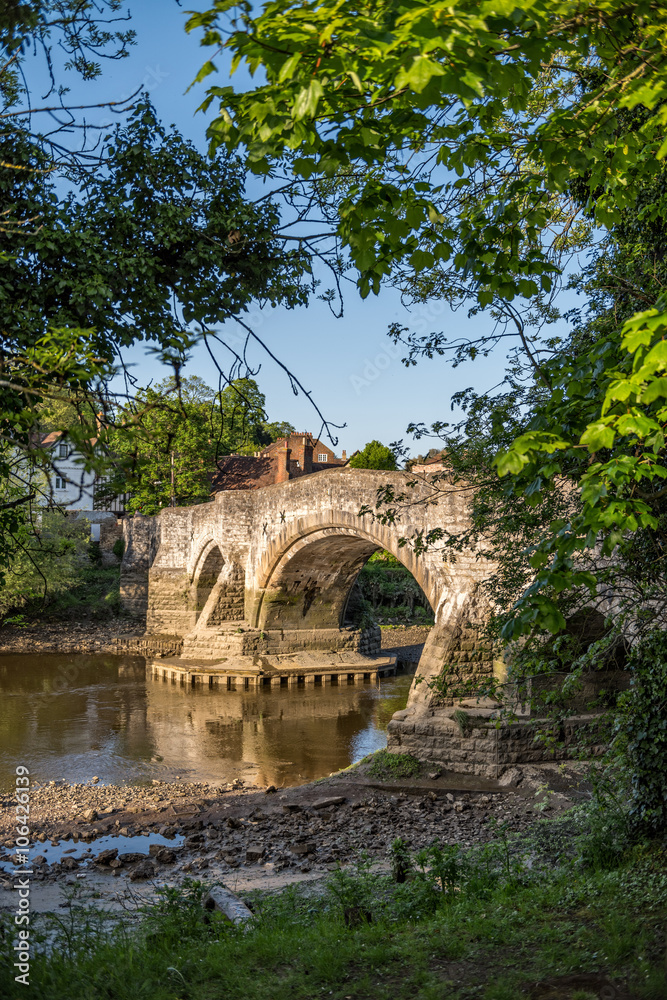 Leaves framed view to medieval Aylesford bridge and river in Kent, England