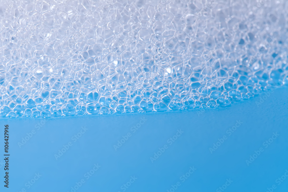 Soap bath bubbles macro view. Laundry detergent, suds textured pattern. White soapsuds on blue background, copy text, horizontal photo. - obrazy, fototapety, plakaty 
