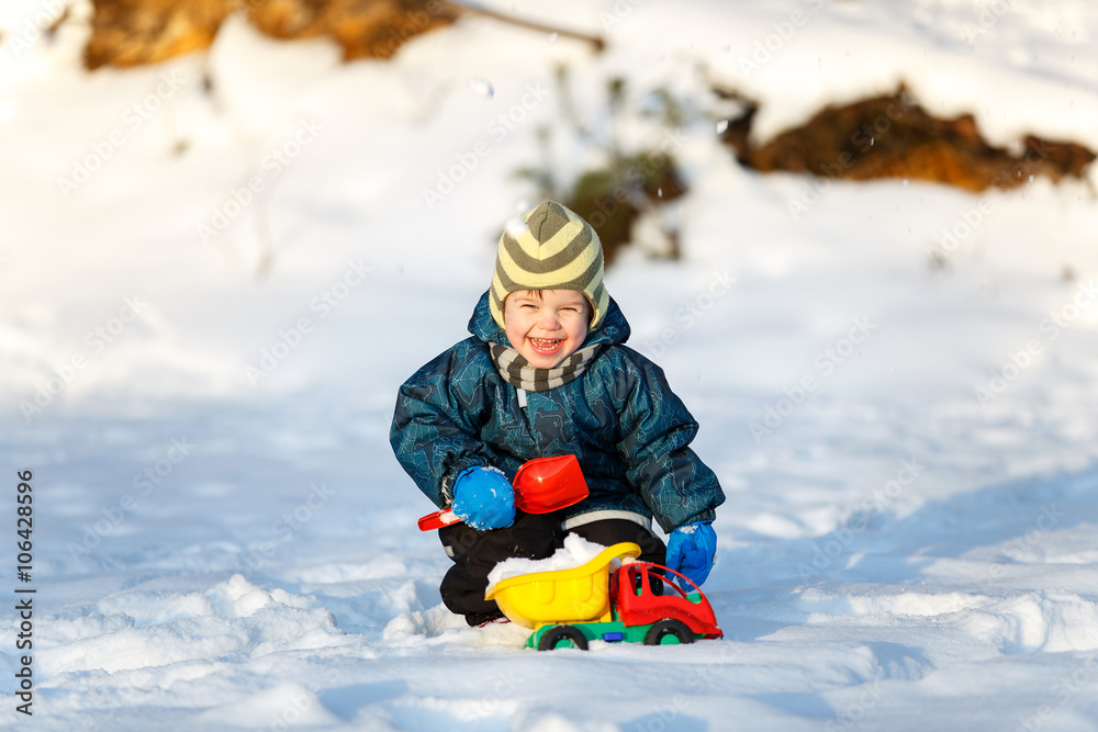Happy boy playing with toy truck on the snow