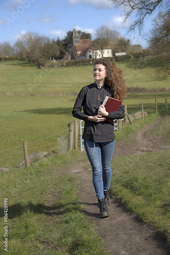 Young parish priest walking in her countryside parish