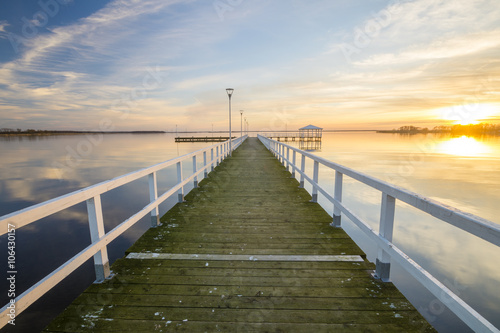 wooden  white pier on the bay at sunset