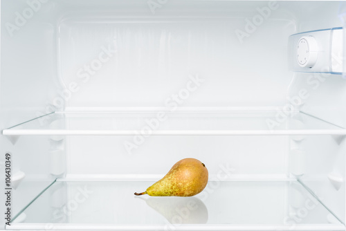 Green pear in empty refrigerator. Diet and hunger concept