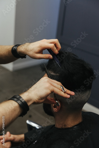 Male barber combing and shaving hair of a male client © Nigrechok