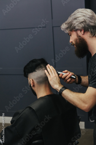 Male barber combing and shaving hair of a male client