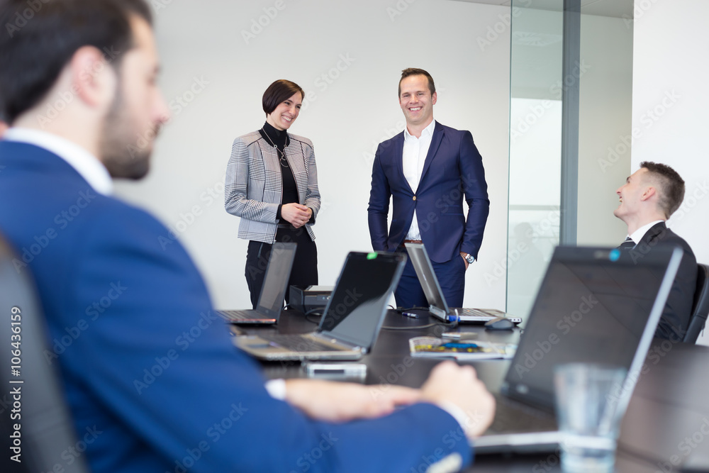 Successful team leader and business owner  leading informal in-house business meeting. Businessman working on laptop in foreground. Business and entrepreneurship concept.