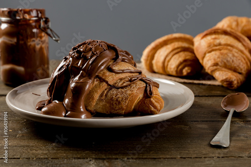 Sweet croissant with chocolate on rustic background