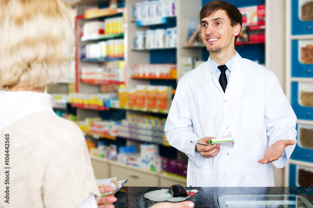 Helpful pharmacist serving young woman in pharmacy