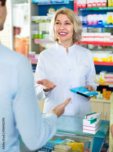 Female pharmacist counseling customer about drugs usage photo