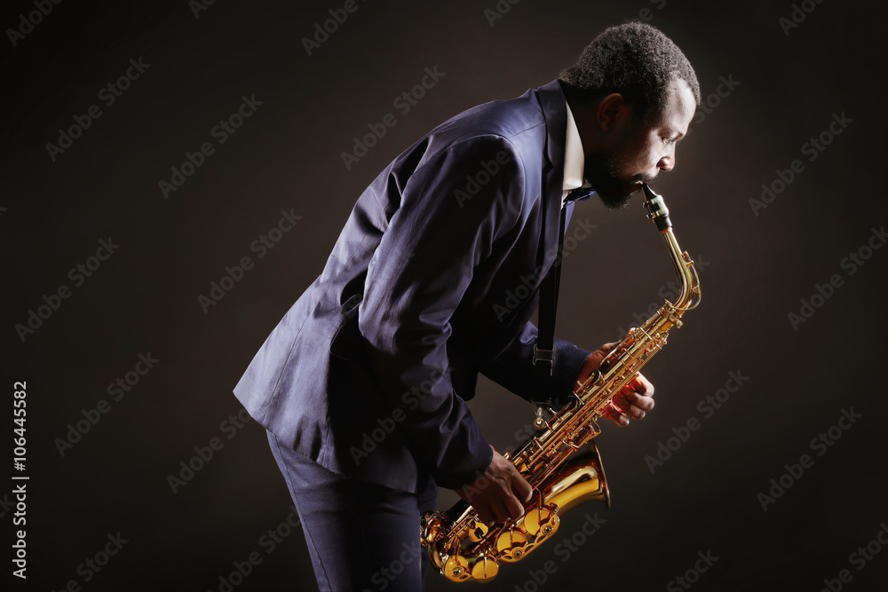 Naklejka premium African American jazz musician playing the saxophone on grey background