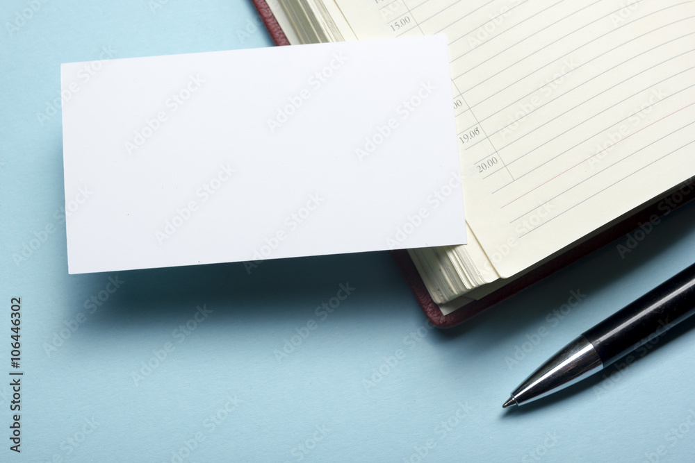 Business card blank over notepad at office table. Corporate stationery branding mock-up Business card blank over notepad at office table. Corporate stationery branding mock-up