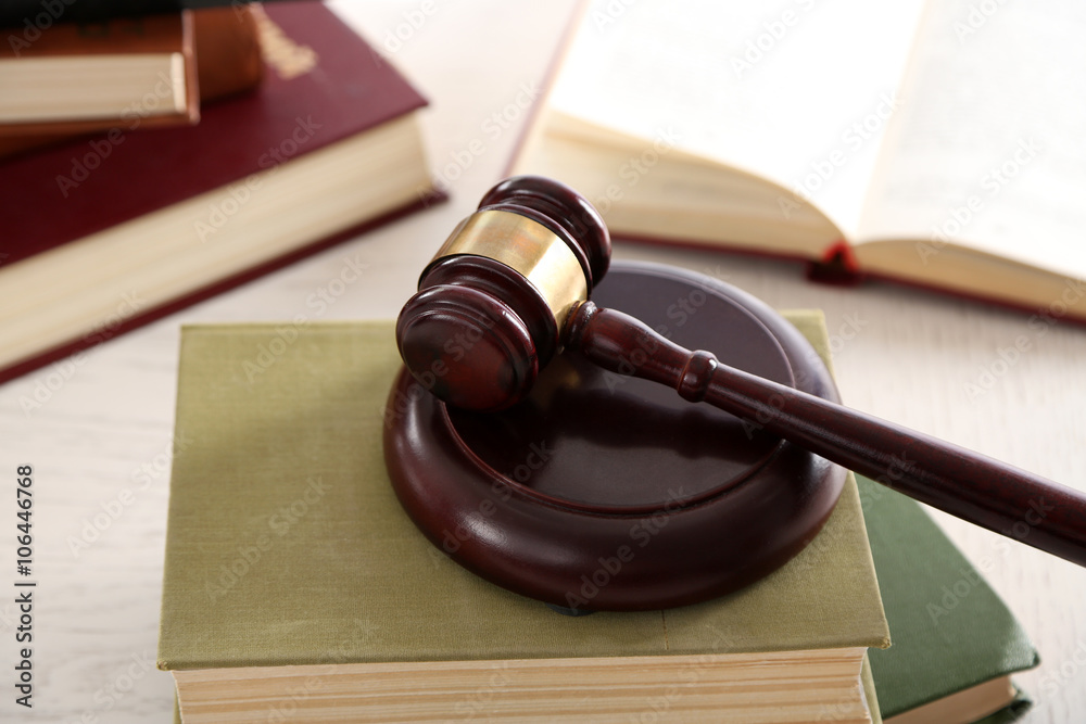 Gavel with books on wooden table closeup