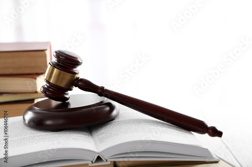 Gavel with pile of books on light blurred background