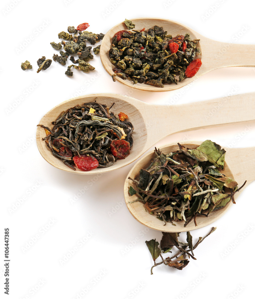Fototapeta premium Variety of tea leaves in wooden spoons, isolated on white