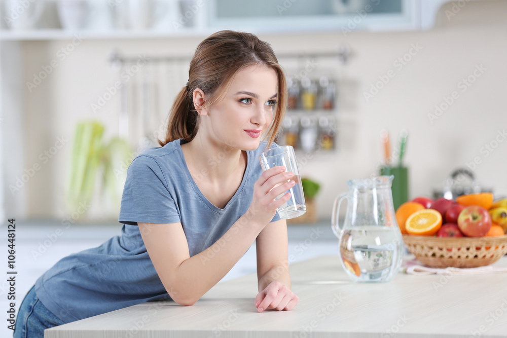 Young woman drinking water from glass in the kitchen Young woman drinking water from glass in the kitchen
