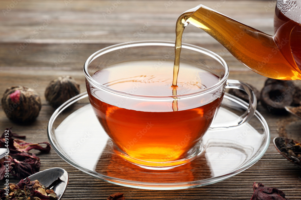 Tea concept. Different kinds of dry tea in spoons. Glass cup of tea on wooden background Tea concept. Different kinds of dry tea in spoons. Glass cup of tea on wooden background