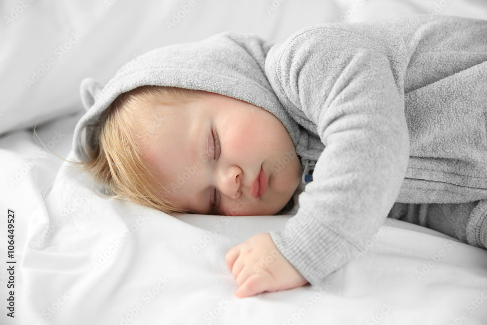 Little baby boy in grey pajamas sleeping on the bed, close up Little baby boy in grey pajamas sleeping on the bed, close up
