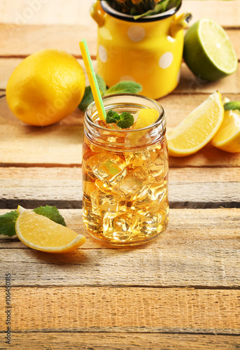 Jar of iced tea with lemon on wooden background