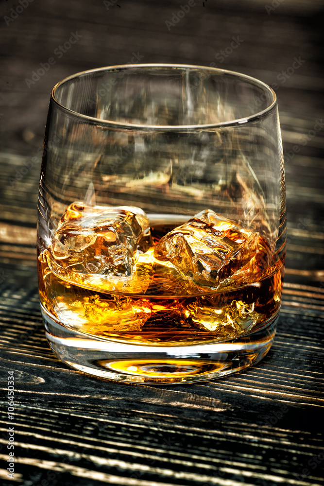 whiskey with ice on a black wooden background
