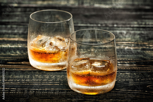 whiskey with ice on a black wooden background,selective focus