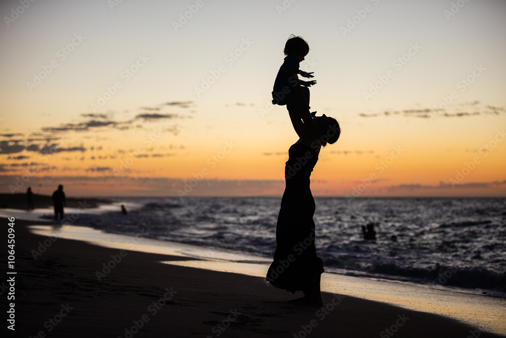 Mother and son having fun on the beach at sunset