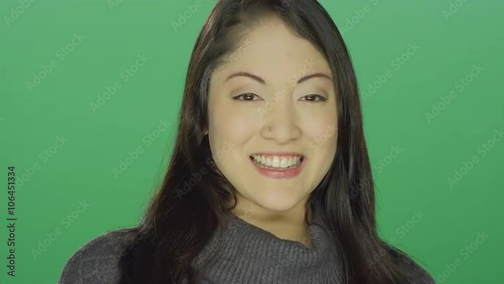 Beautiful young Asian woman smiling and flirting, on a green screen studio background Beautiful young Asian woman smiling and flirting, on a green screen studio background