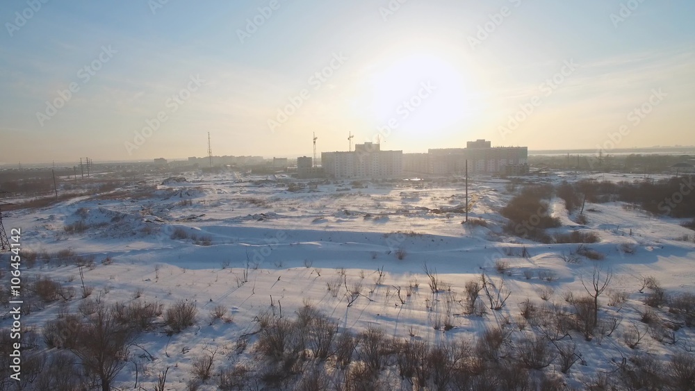 flying over the field towards the city at sunset. aerial video
