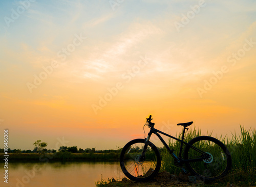 silhouette MTB, bicycle in grass at sunset