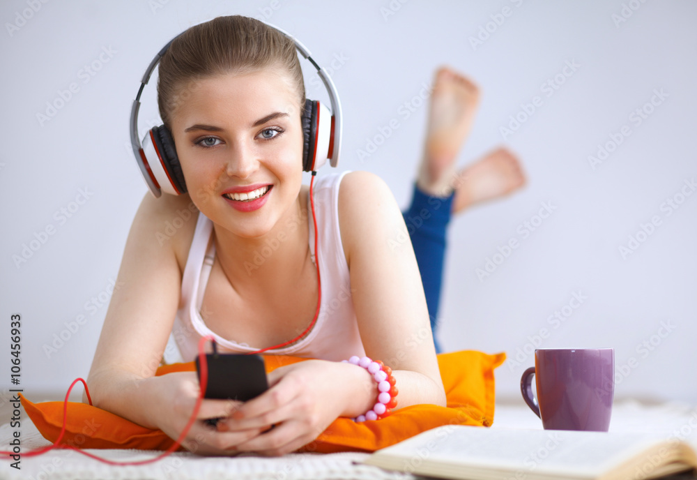 Naklejka premium Young woman lying on floor and listen to music
