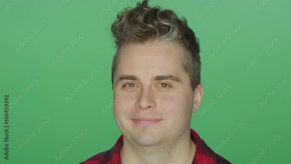 Young man smiling and then leaning his head back, on a green screen studio background