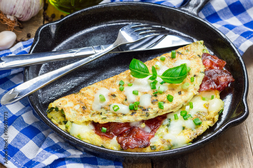 Bacon stuffed omelette with backed beans on a iron cast pan