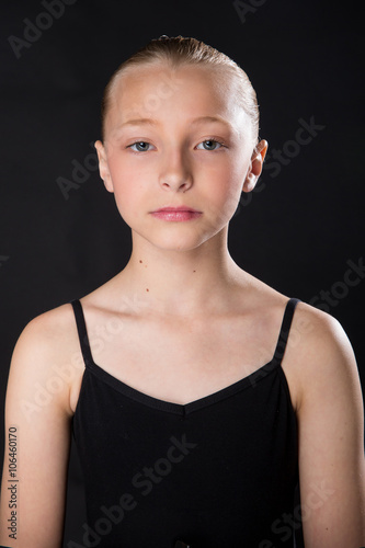 Serious young girl head shot portrait on black background