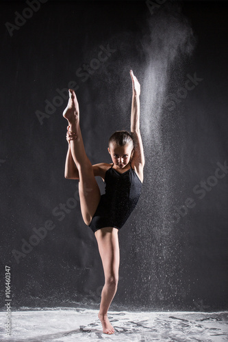 Young ballet dancer with flying powder doing the splits