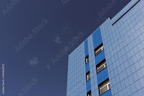 Modern blue office building against blue sky.