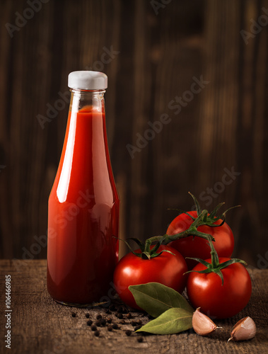 Dark still life with ketchup and ingredients on the rough wood