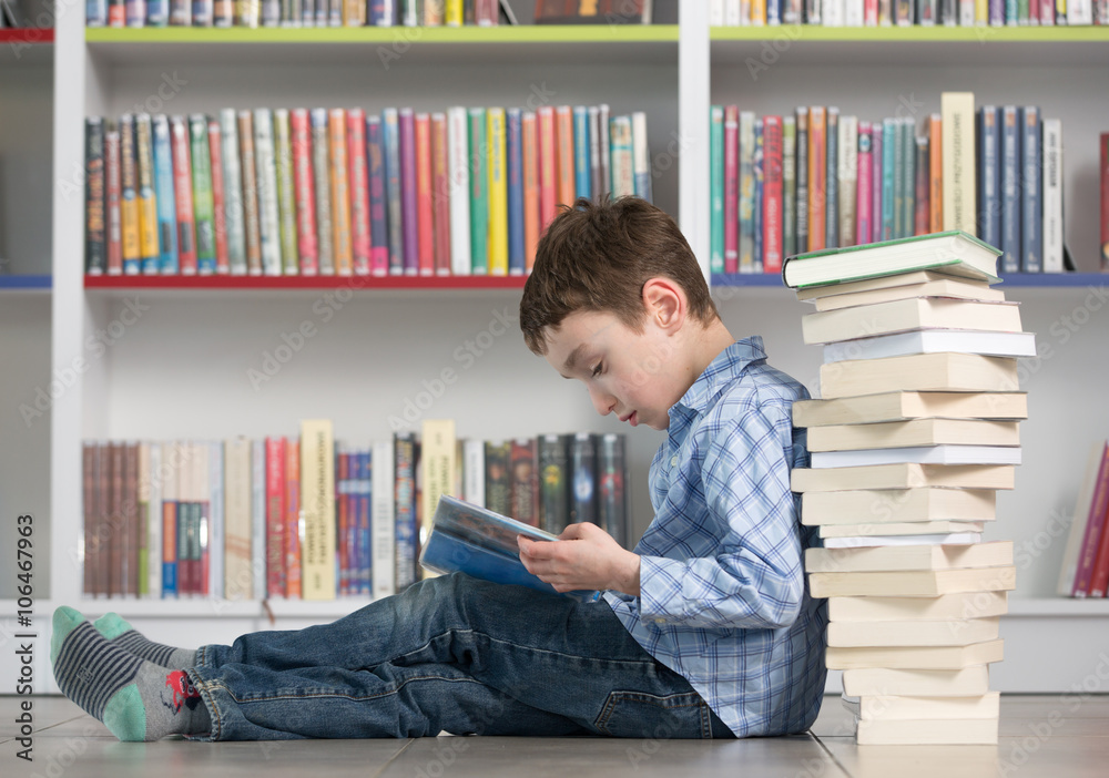 Cute boy reading book in library