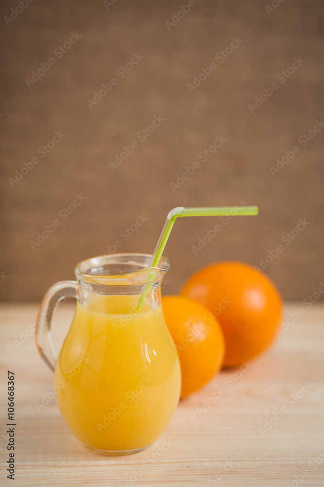 Fototapeta premium Orange juice in clear jar on a wooden background