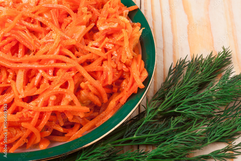 Hot carrot salad in plate on wooden background Hot carrot salad in plate on wooden background