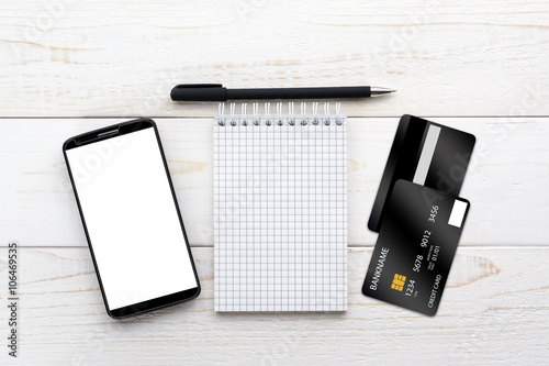 Smartphone, notebook and credit card on a white table