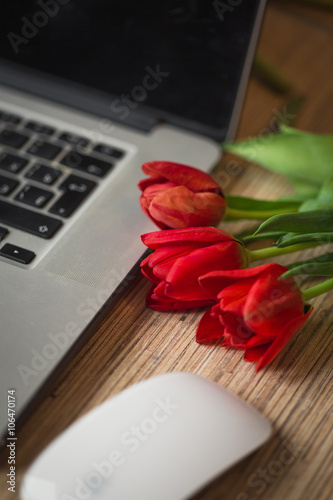 Fototapeta Naklejka Na Ścianę i Meble -  Desk with a computer and bouquet of tulips