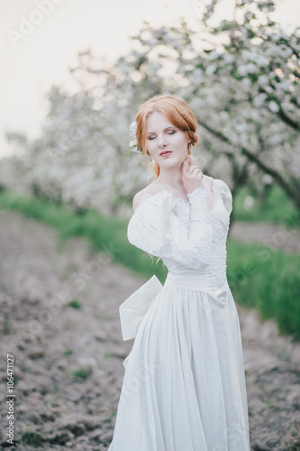 Beautiful bride in a vintage wedding dress posing in a blooming apple garden. Spring mood