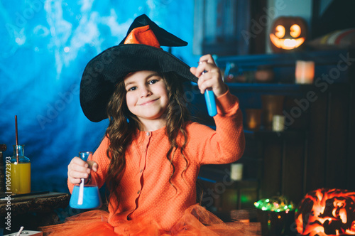 Little girl in a costume of witch making potion photo