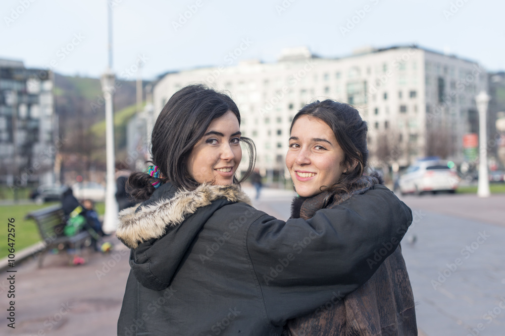 Two smiling woman friends in the street.