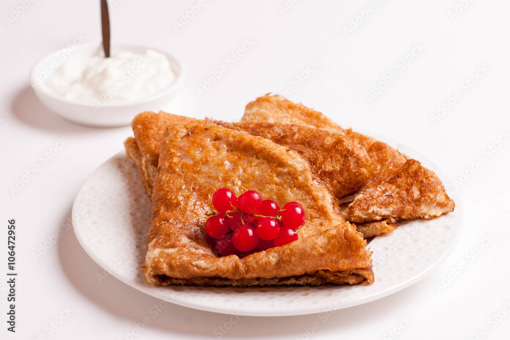 crepes with red currants and sour cream on a plate isolated crepes with red currants and sour cream on a plate isolated