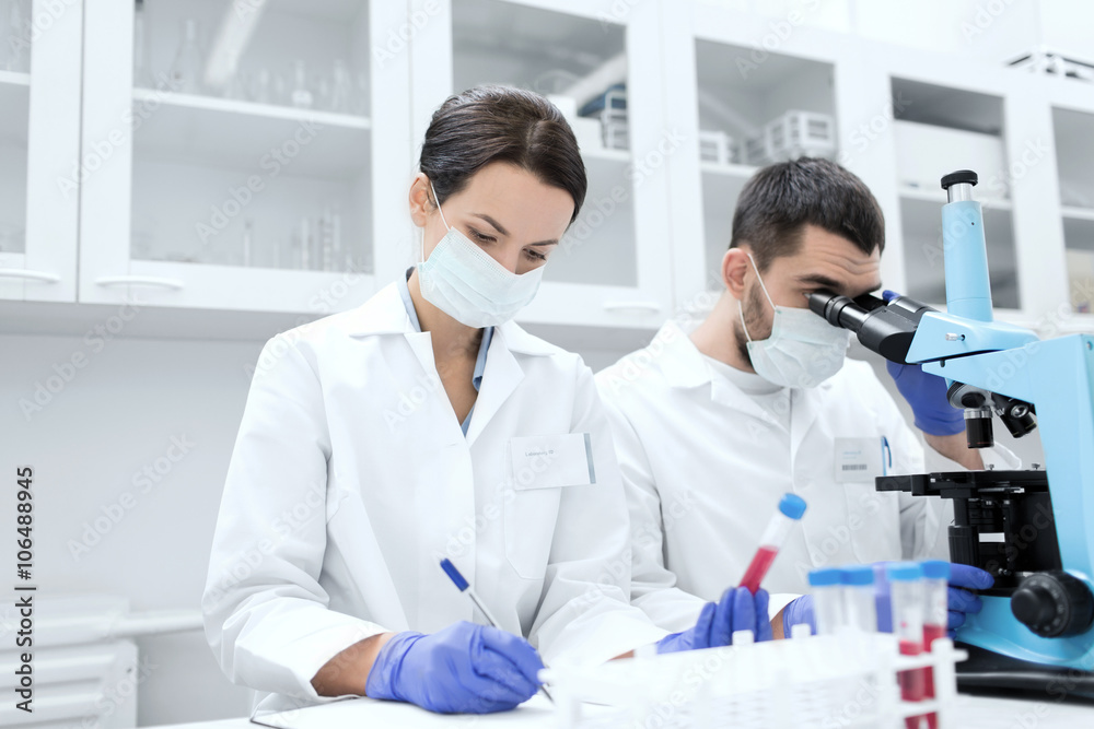 scientists with clipboard and microscope in lab scientists with clipboard and microscope in lab