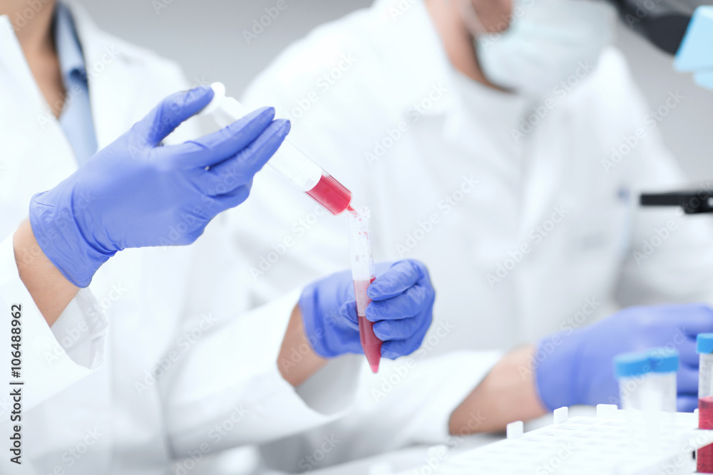 Fototapeta premium close up of scientists hands with test tube in lab