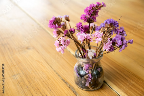 Purple flowers in a glass vase on wood table