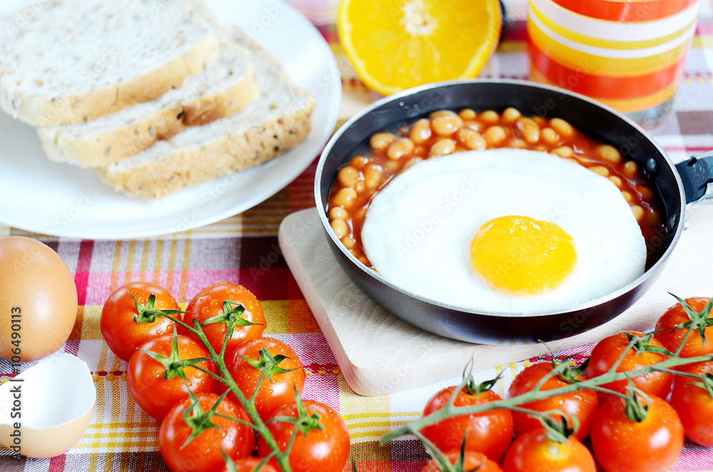 Fried egg with beans, toast bread, fresh juice, tomatoes and oranges Fried egg with beans, toast bread, fresh juice, tomatoes and oranges