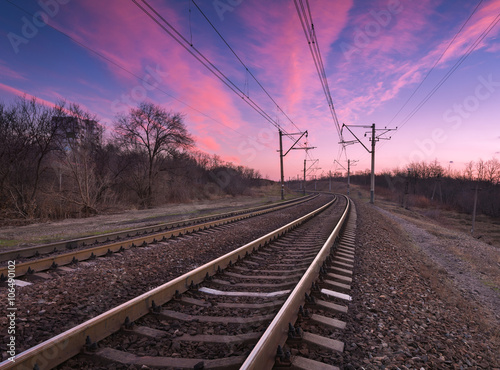 Railroad at colorful sunset on the background of beautiful blue sky. Railway landscape