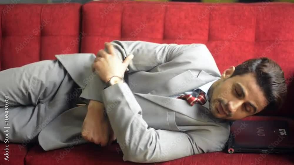 Locked-on shot of a businessman lying on sofa Locked-on shot of a businessman lying on sofa