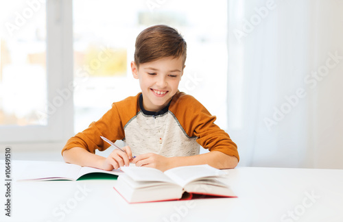 smiling student boy writing to notebook at home